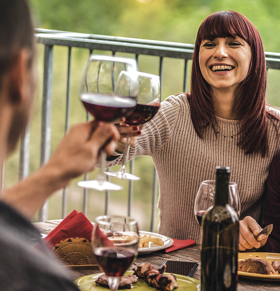 Couple having dinner and clinking glasses of red wine